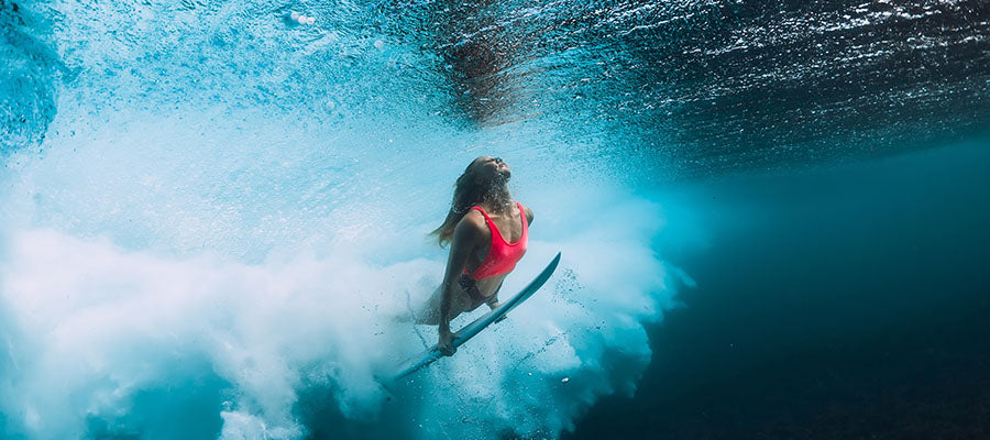 Female surfer cresting underneath the waves waiting for the best one.