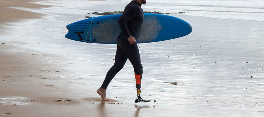 Surfer carrying his board on the shoreline waking to the water.