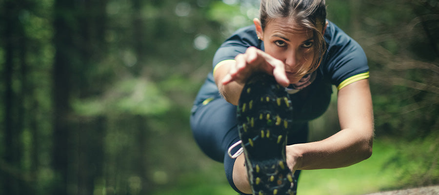 Athletic woman stretching before a run in the woods.