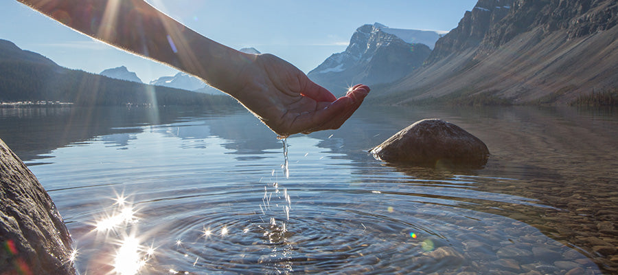 Person cupping water in their hand in a mountain runoff lake.