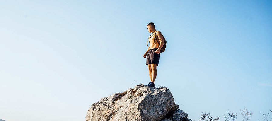 Athletic man standing on top of a large rock.