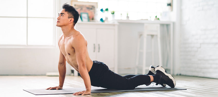 Athletic male stretching on a yoga mat