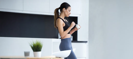 Woman in workout clothes eating something in a modern kitchen