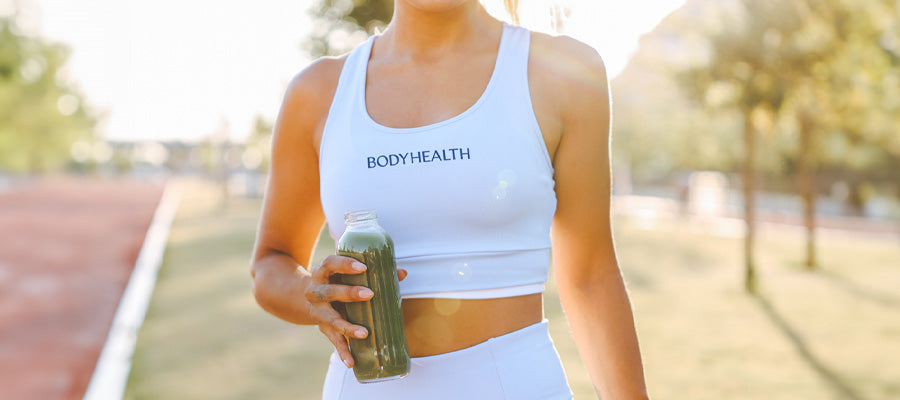 athletic woman at a track meet drinking PerfectAmino and Greens