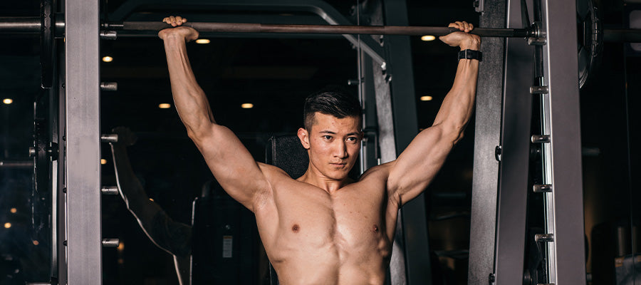 athletic man doing shoulder press with weights in the gym