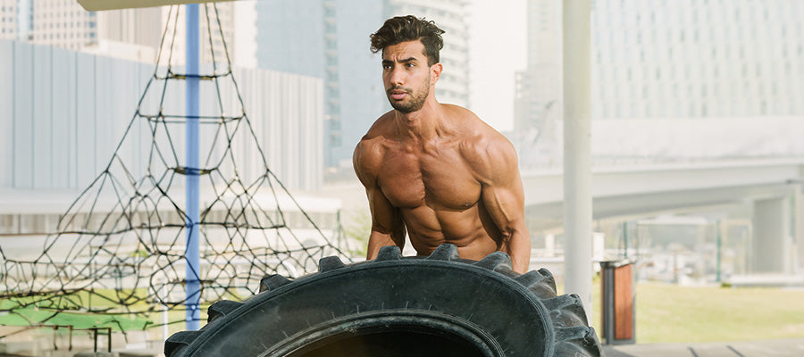 athletic male lifting a tractor tire  for a workout