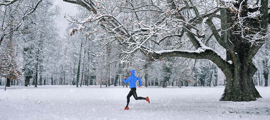 Athletic person going for a run in a snowy forest.
