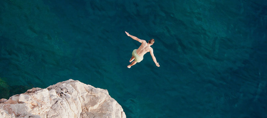 Person cliff diving into a large body of water.