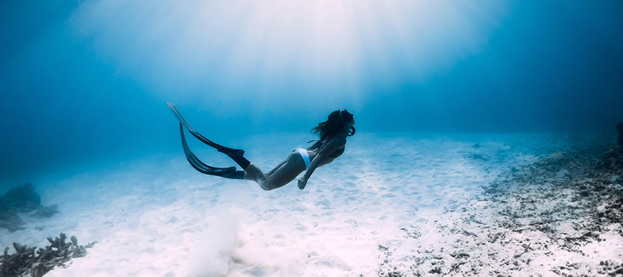 Athletic Female free diver under the water near the bottom.