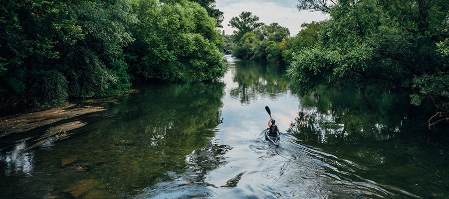Kayaker going through the river in the woods.