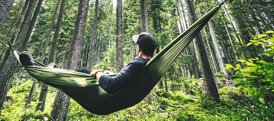 Man relaxing in a hammock in the middle of the forest alone.