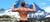 Male bodybuilder showing off his shoulder muscles with a blue snowy mountain in the background.