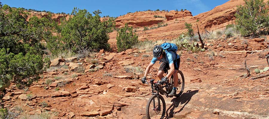 Athletic cyclist going down a rocky hillside in the desert.