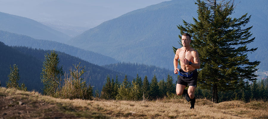 Athletic male running with blue mountains in the background.