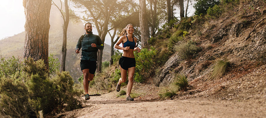 Athletic Man and Woman running on a dirt path in a park.