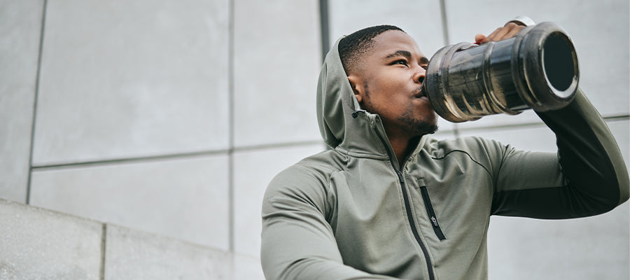 Male Athlethe drinking PerfectAmino Electrolytes and sitting on some stairs resting