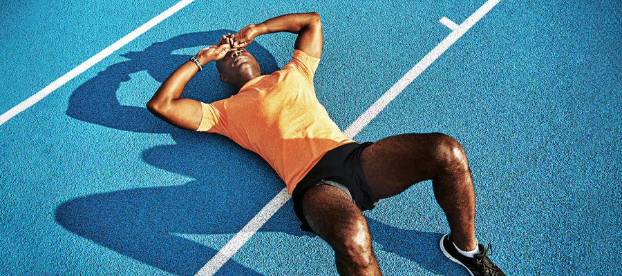 Athletic man resting after running on a track field.