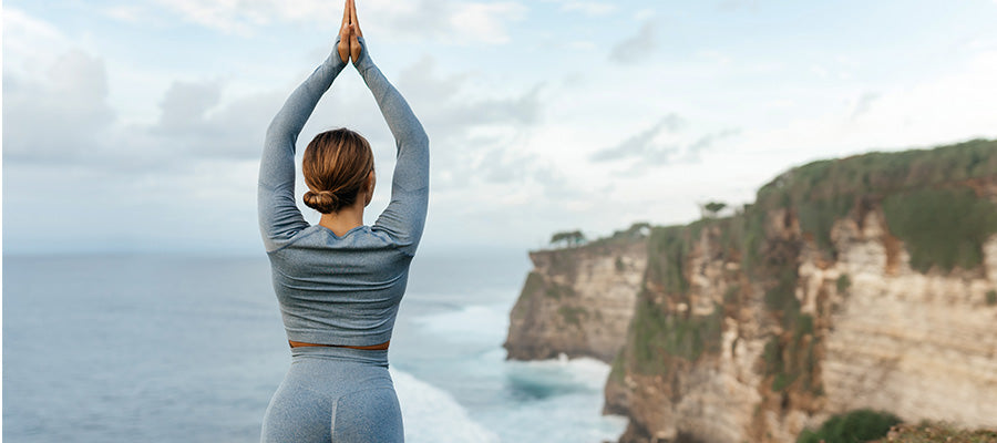 Athletic woman doing yoga on a cliff overlooking the ocean.