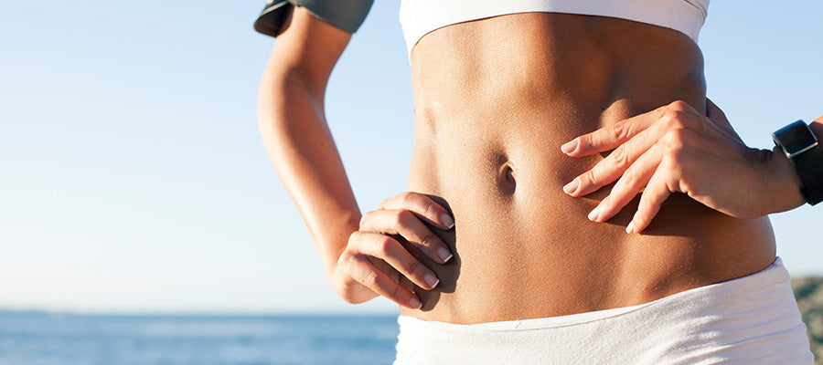 Athletic stomach of a person with a large body of water behind them.