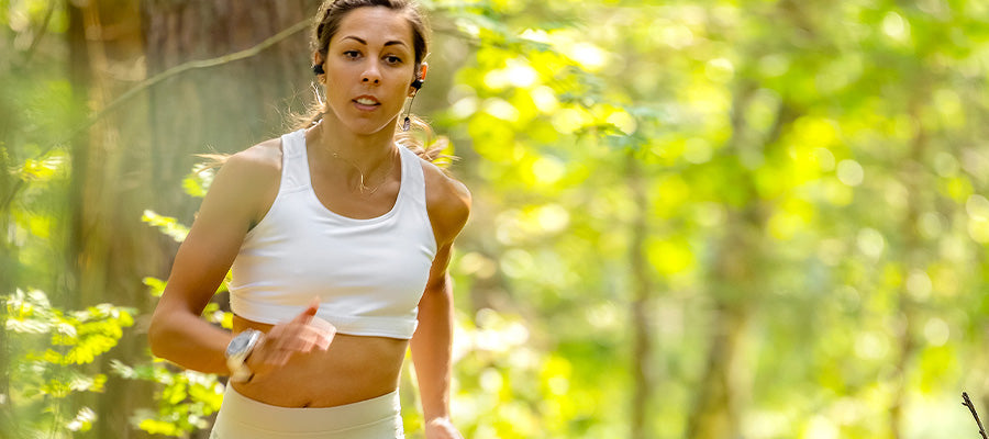 Athletic female jogging in a sunny forest.