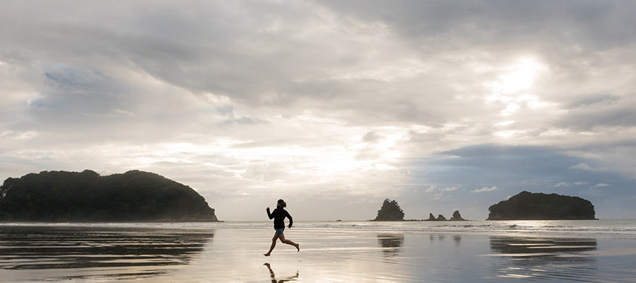 Person running during low tide on water in the mountains.