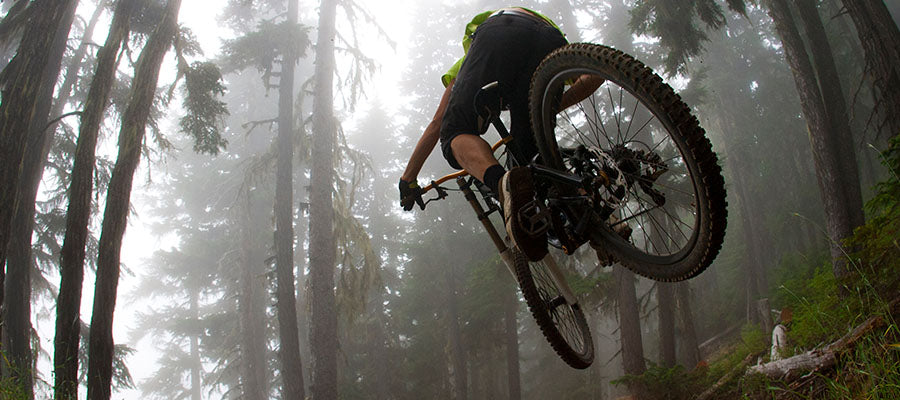 Mountain Bike rider going through a foggy forest area.