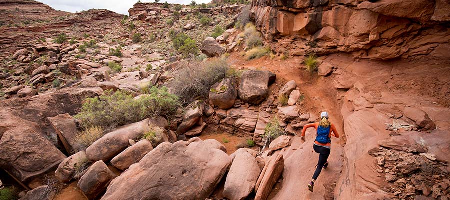 Athletic woman running through desert cliffs.