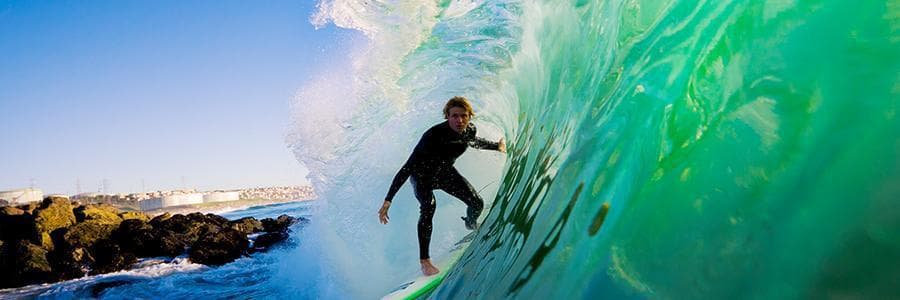 Man surfing on the inside of a pipeline with emerald green waves.
