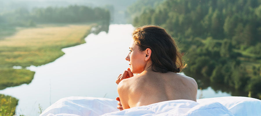 Athletic woman relaxing on a blanket above a forest and a river.