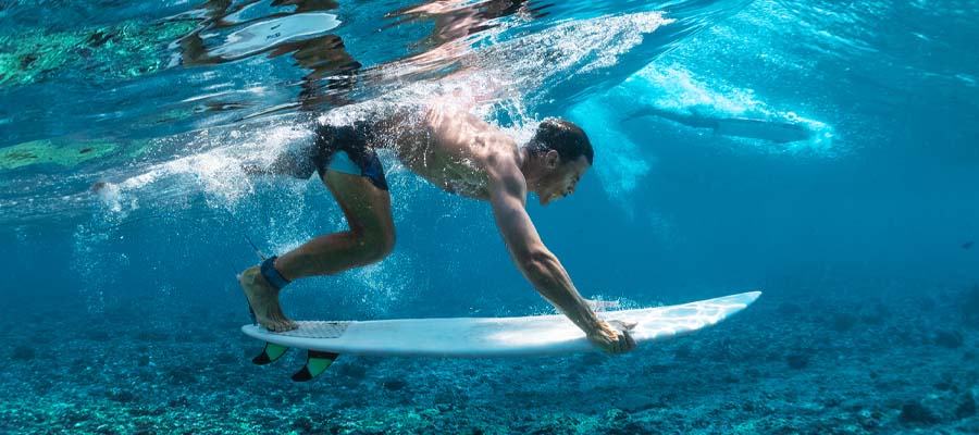 Surfer diving under the water with his board looking for the right wave.