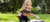 A little girl on the back of an athletic woman, enjoying the park.