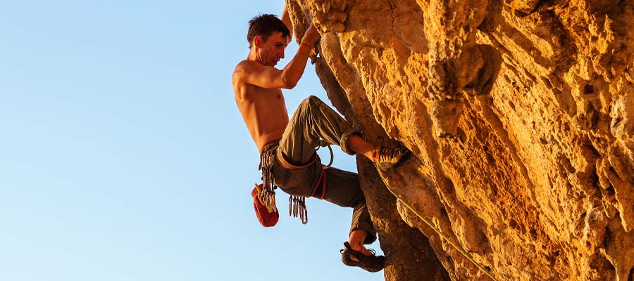 Athletic man free climbing on a mountain side.
