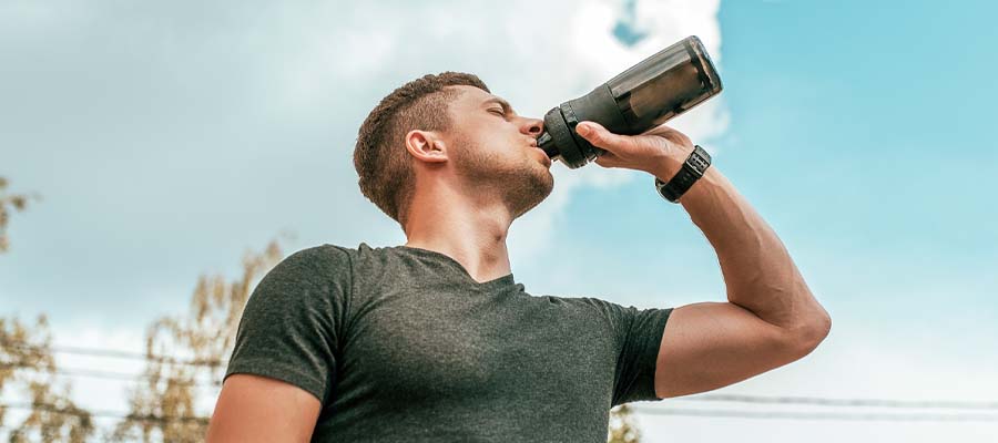 Athletic man drinking PerfectAmino Powder from a shaker bottle.