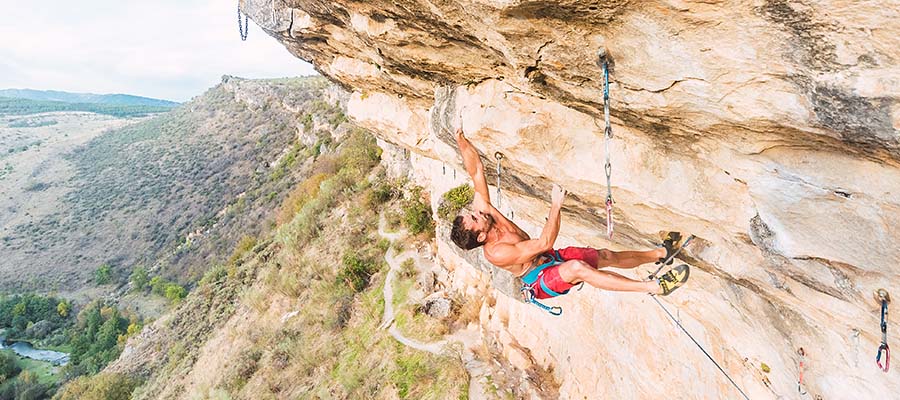 Athletic male rock climbing on a mountain cliff.