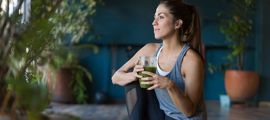 Athletic woman having a moment of reflection while enjoying a drink of Greens.