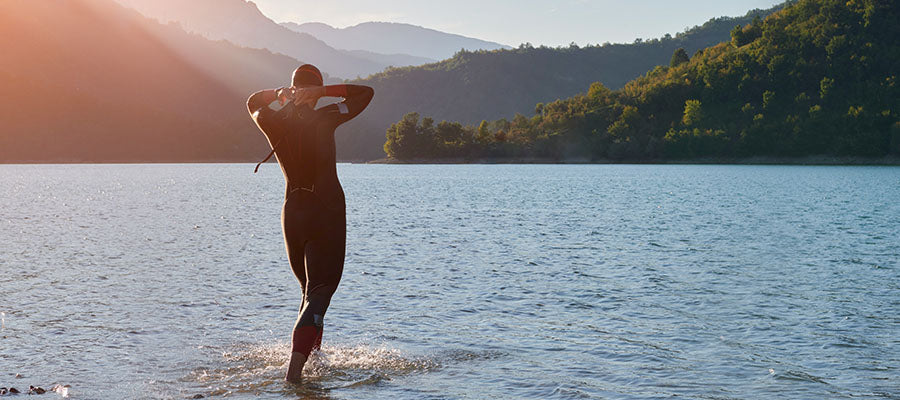 Athletic person in a we suite getting ready to go for a dive in a lake in the mountains.