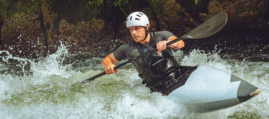 Male white water kayaking in a river through the mountains.