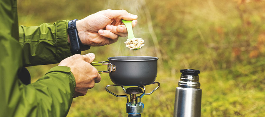 Survivalist in the mountains making a small dinner with a small personal camp oven.