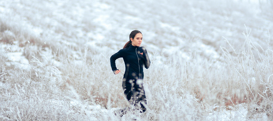 Athletic woman running in a snowy field. 