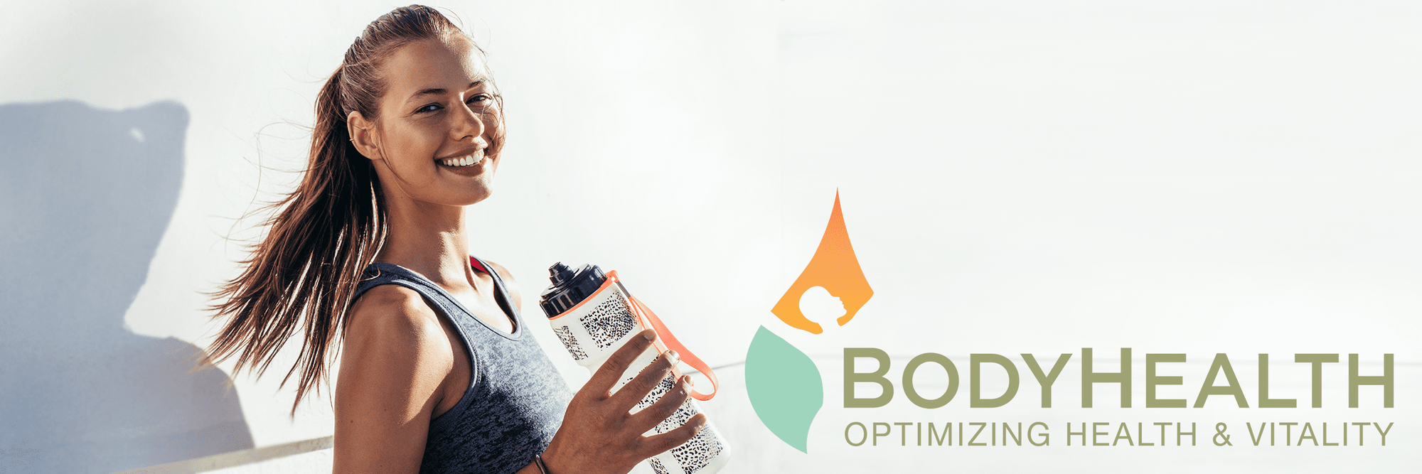 Athletic female drinking from a water bottle after running.