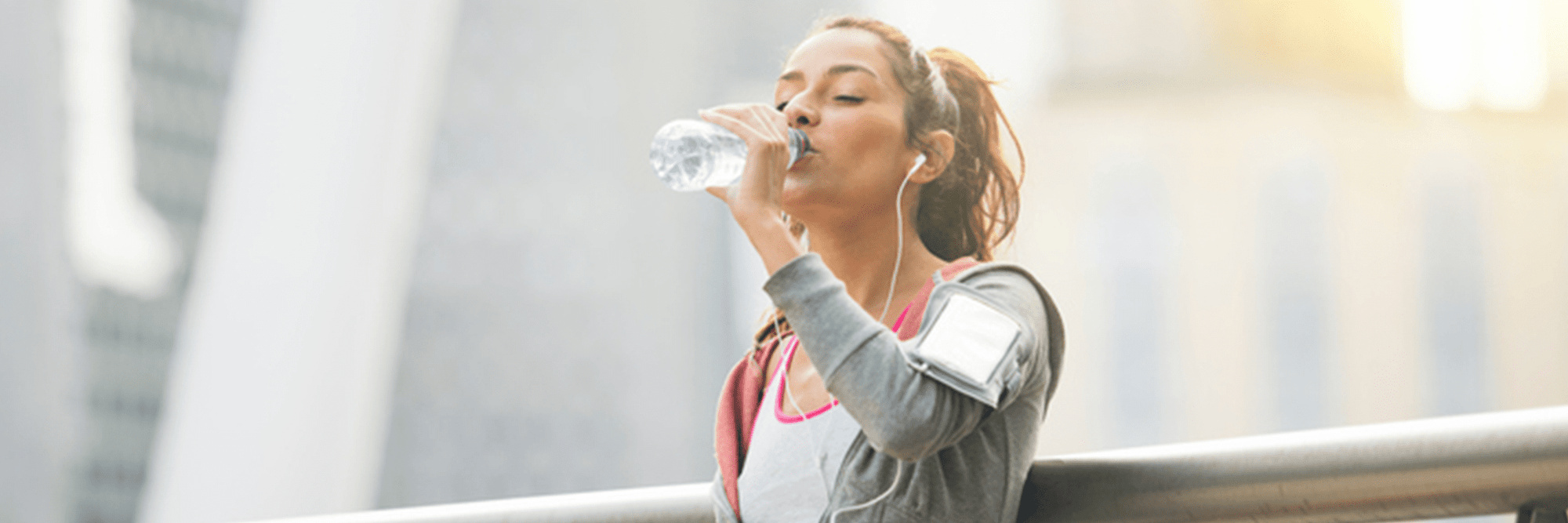 Healthy woman drinking water on a city street.