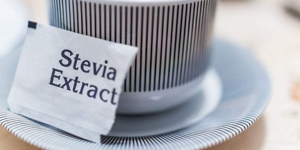 A packet of stevia resting against a cup of coffee. The Hidden Dangers Of Stevia Leaf Sweetener Sugar Substitutes